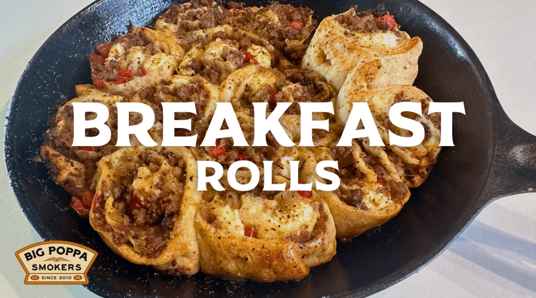 Golden breakfast rolls filled with sausage, cheese, and peppers in a cast iron skillet, with "Breakfast Rolls" text and Big Poppa Smokers logo.