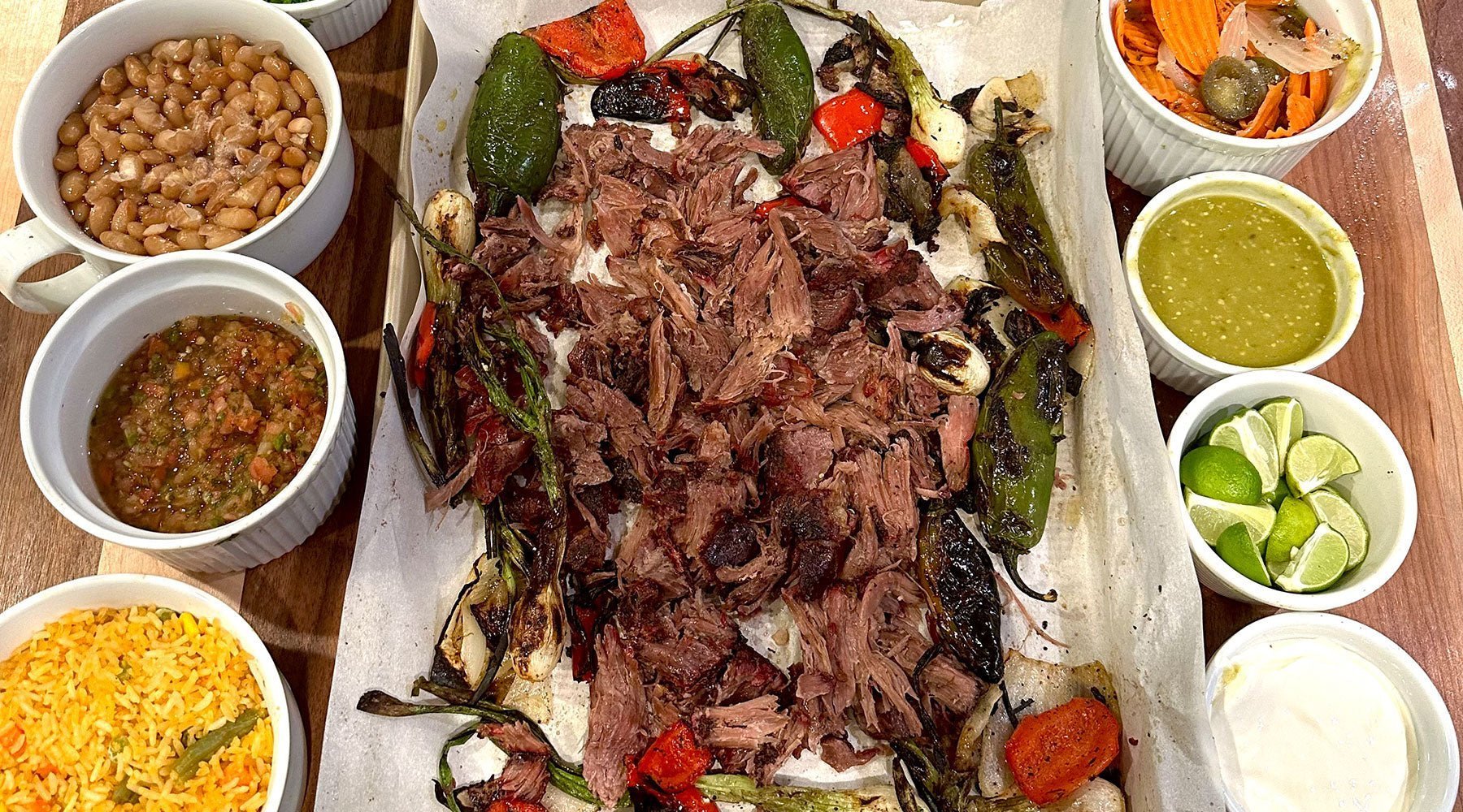 Thor Hammer Tacos served with meat on a platter, surrounded by rice, beans, guacamole, sour cream, and classic taco toppings