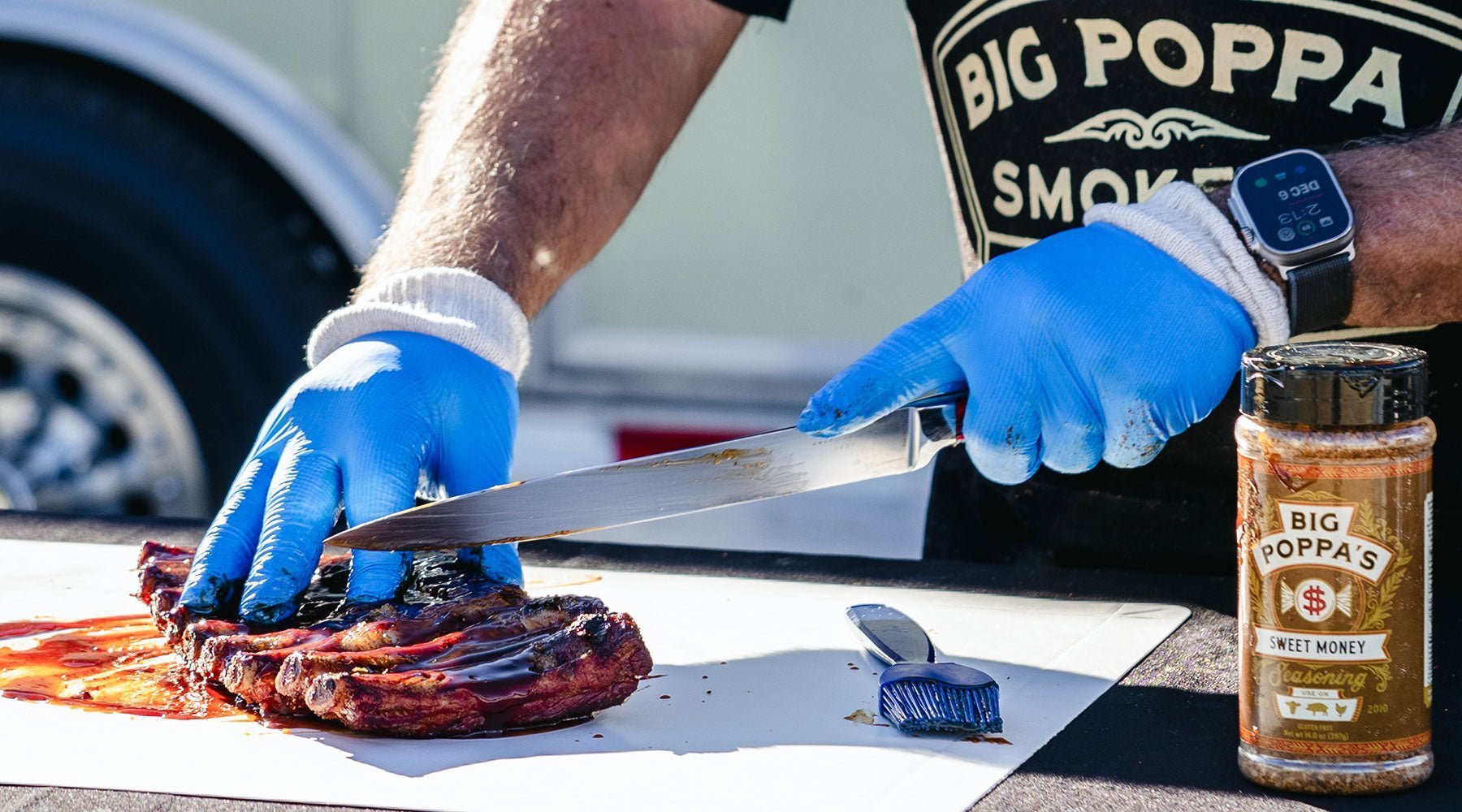 Slicing of ribs with a Lamson knife on a cutting board with his gloves on.