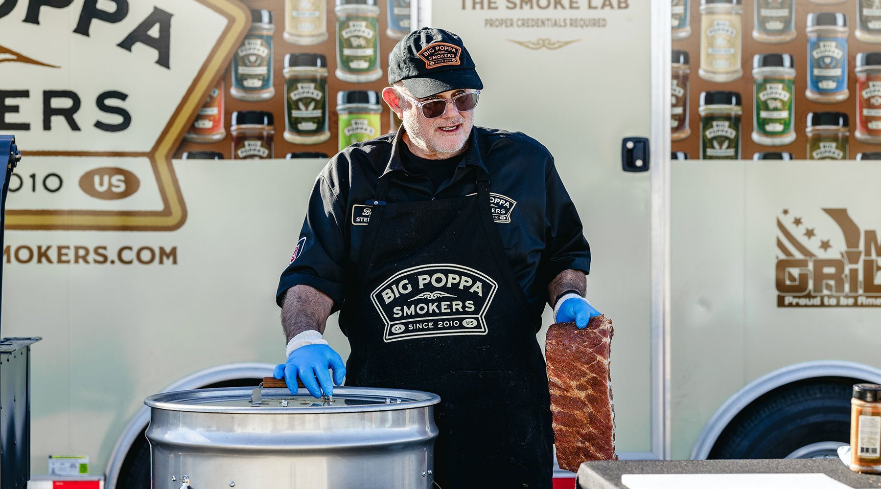 Big Poppa putting a slab of ribs on the drum smoker