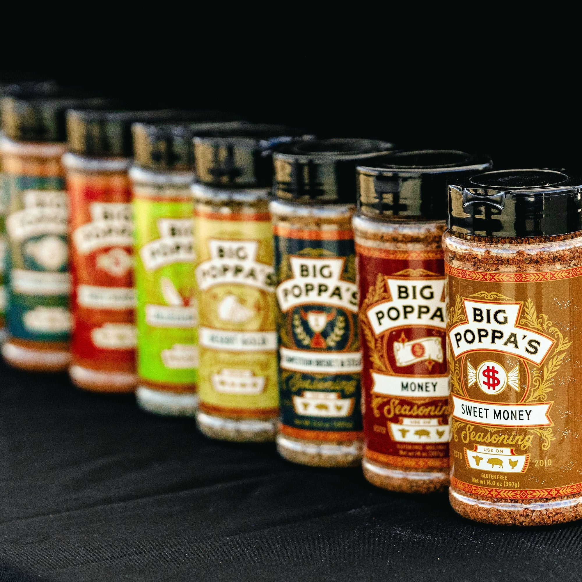 All of the Big Poppa Smokers seasoning lined up on a black table.