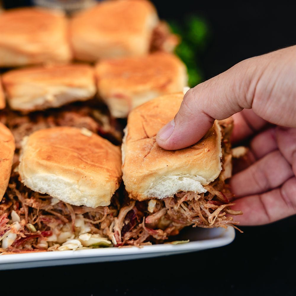 Hand reaching for bbq pulled pork sandwich