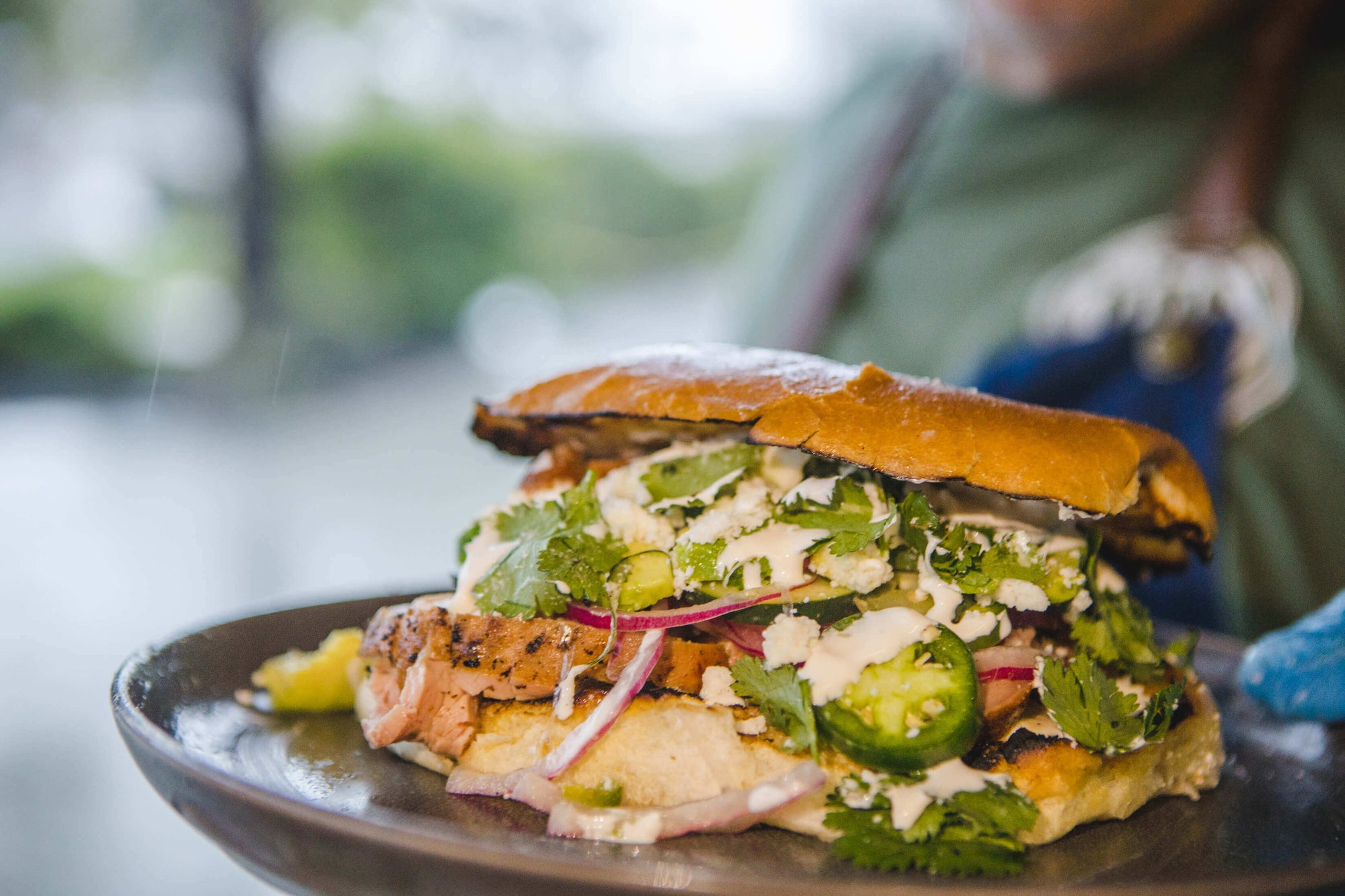 Large sandwich with various ingredients on a plate, blurred background