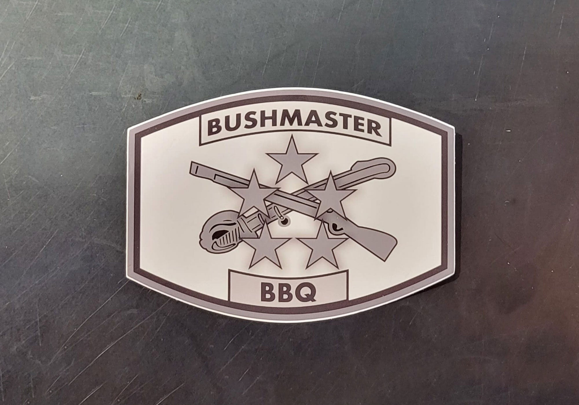 Logo of Bushmaster BBQ that has stars, guns and sword to symbolize Chris' journey in the military and continued service.