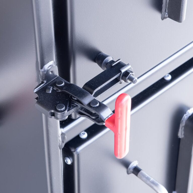 Close-up of the latch mechanism on the Meadow Creek BX50 smoker, featuring a red handle and a black metal latch assembly.