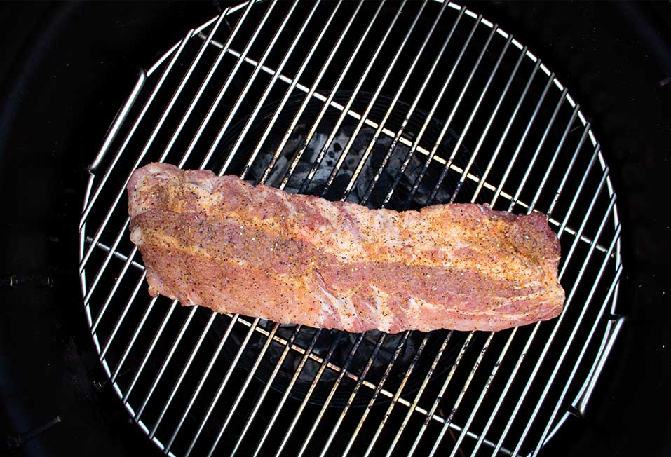 A slab of meat seasoned with Big Poppa's Sweet Money on a grill, highlighting the seasoning's rich color and textured surface.