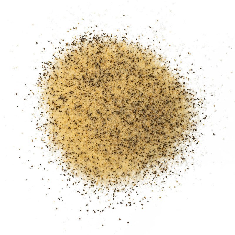 A close-up of Boars Night Out Spicy White Lightning seasoning spread out on a white surface. The seasoning is a coarse blend of white and black particles, likely consisting of salt and various spices.