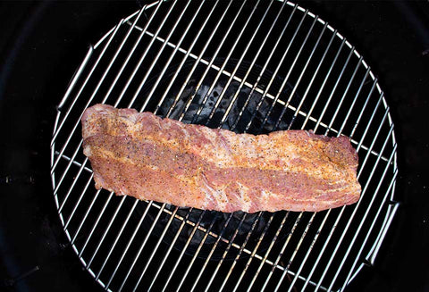 A slab of meat seasoned with Big Poppa's Sweet Money Seasoning on a grill grate, showing the seasoning's rich color and texture on the surface of the meat.