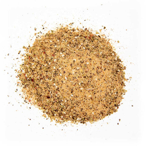 Close-up of beige seasoning powder with visible grains of salt and flecks of red chili and herbs, ideal for various dishes, displayed on a white background.