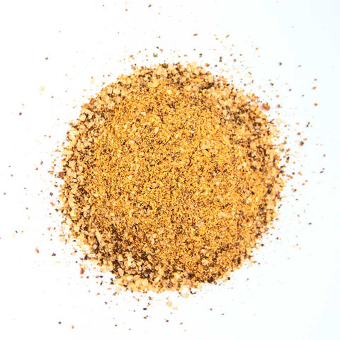 A heap of brown and golden coarse seasoning blend, consisting of various spices and salt, isolated on a white background.