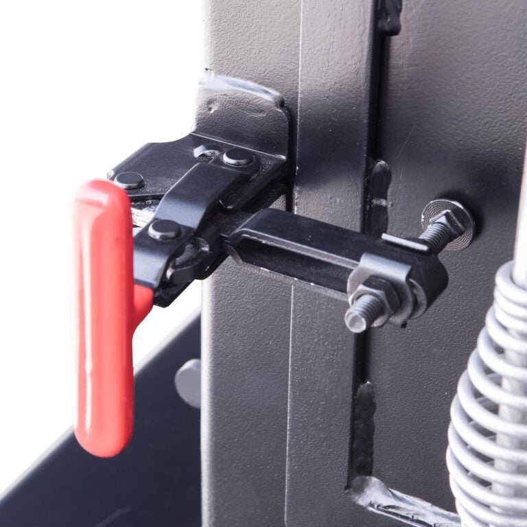 Close-up of a black metal latch with a red handle, attached to the side of a barbecue smoker's firebox