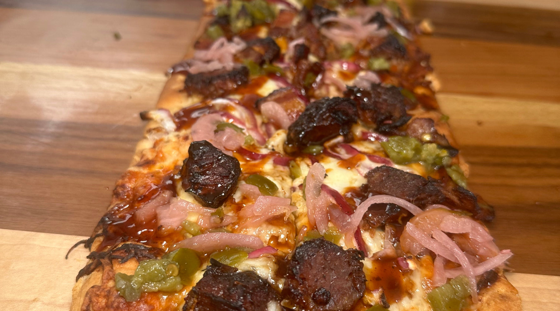 Flatbread that has been cooked on the pellet smoker and topped with BBQ sauce, burnt ends, and all of your favorite toppings and don't forget all of the cheesey goodness.e