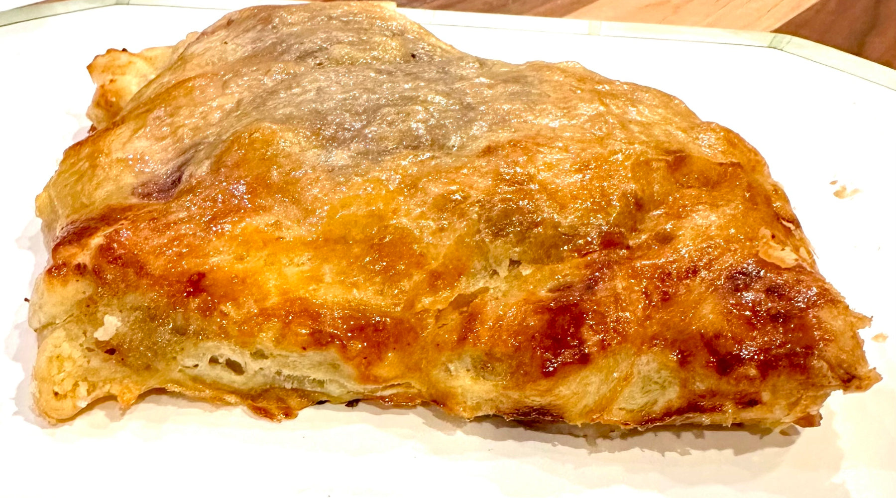 Golden-brown puff pastry with a flaky, crisp crust and a glossy surface, resting on a white plate.