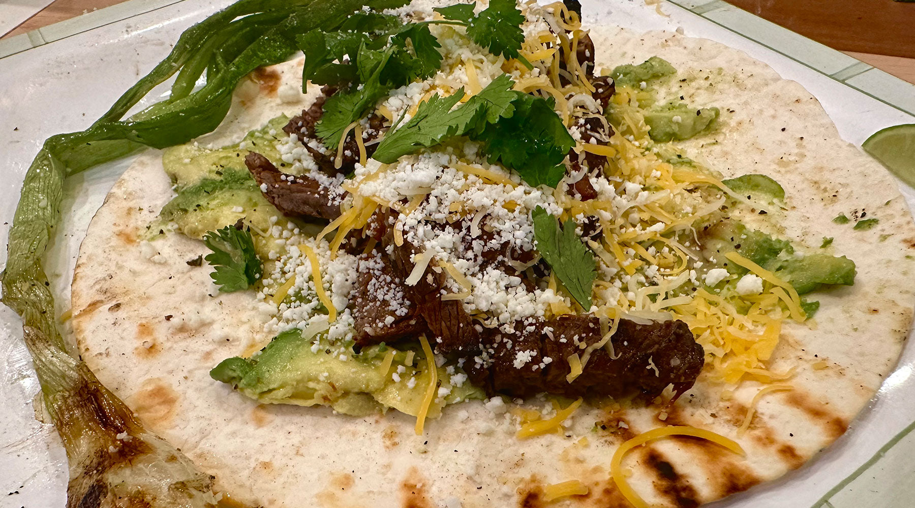 Plate of carne asada on a tortilla with toppings - keto friendly dish.