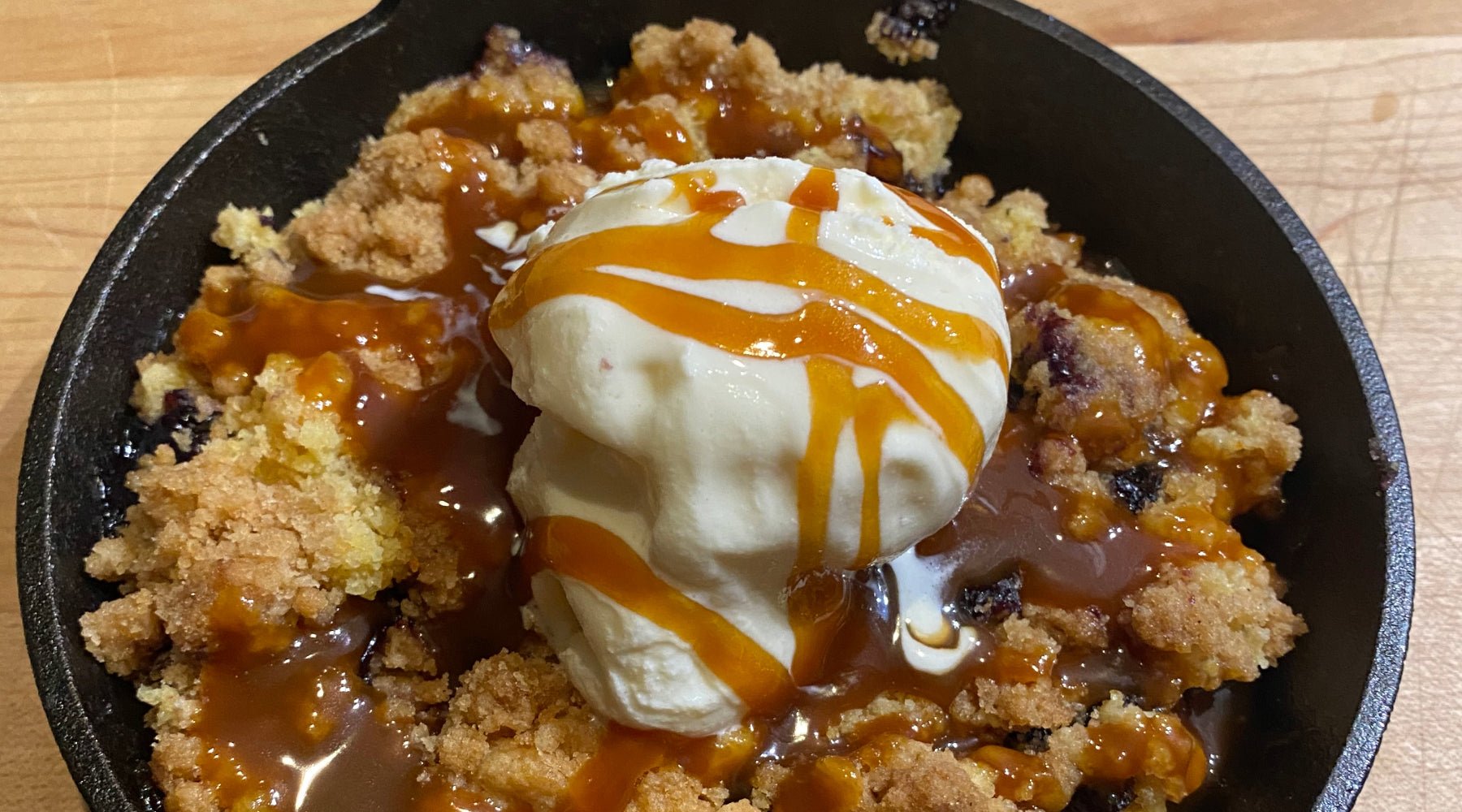 Cast iron dish with blueberry crumble cake with ice cream