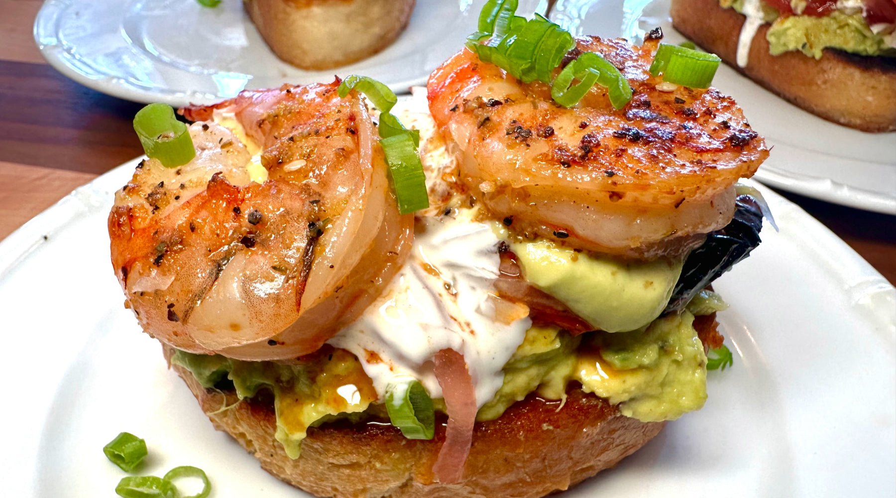 Thick cut of toasted bread topped with avocado, onions and grilled shrimp