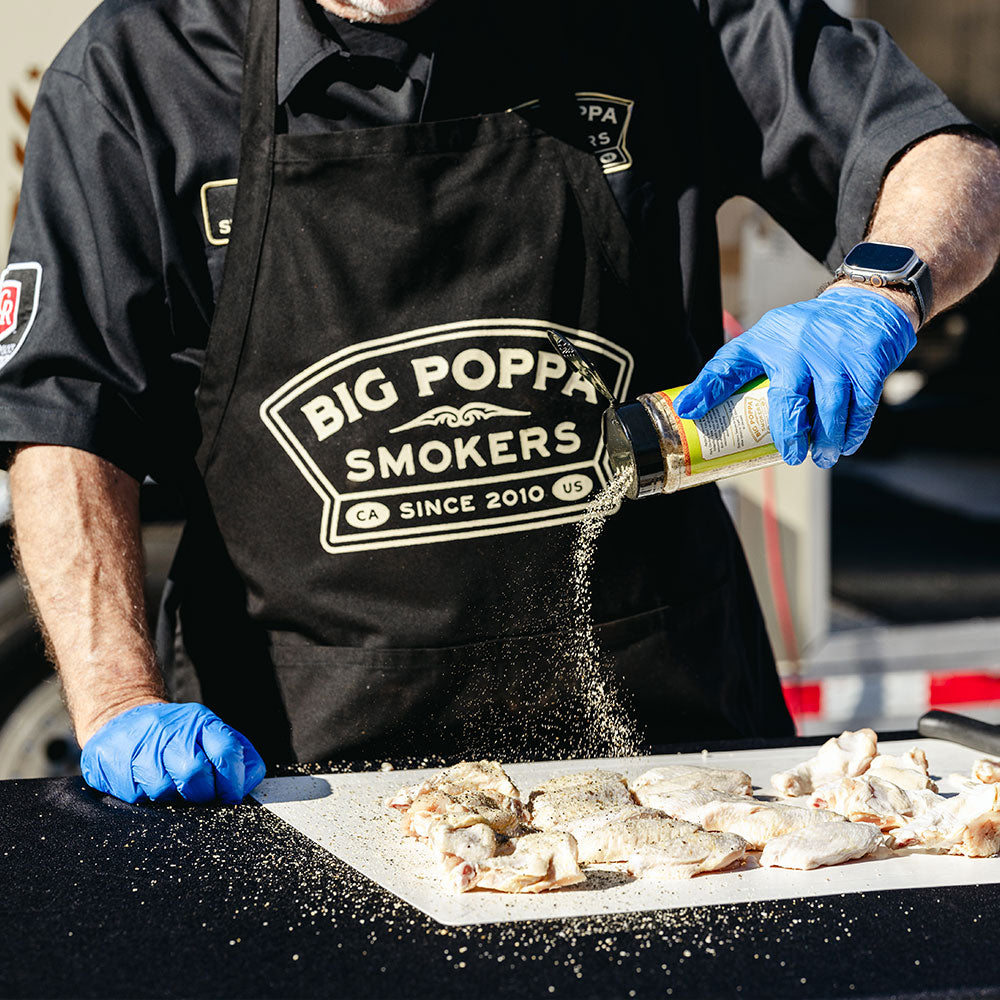 Big Poppa seasoning his chicken wings with Jallelujah Lime, while wearing his blue food safety grade gloves.