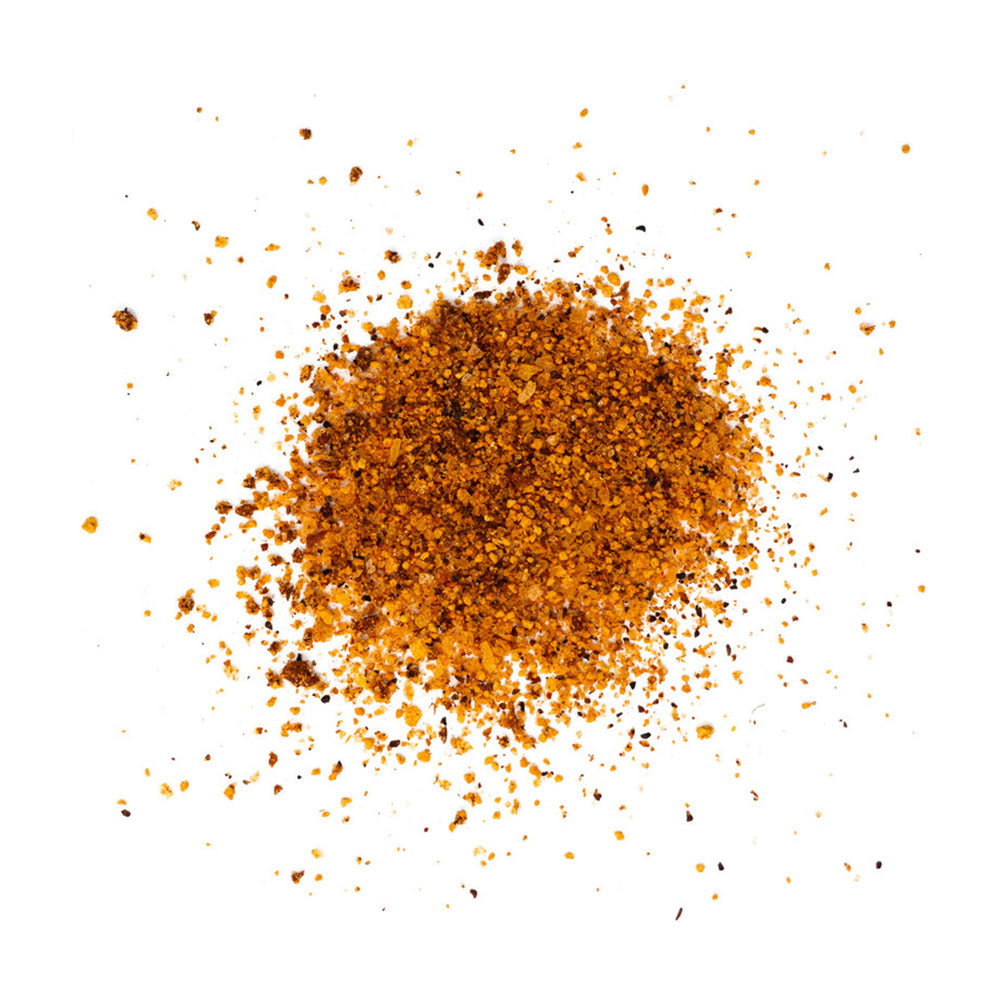 A close-up image of LC BBQ Pork Dry Rub spices scattered on a white surface. The rub consists of various spices, creating a textured mix of red and brown granules.