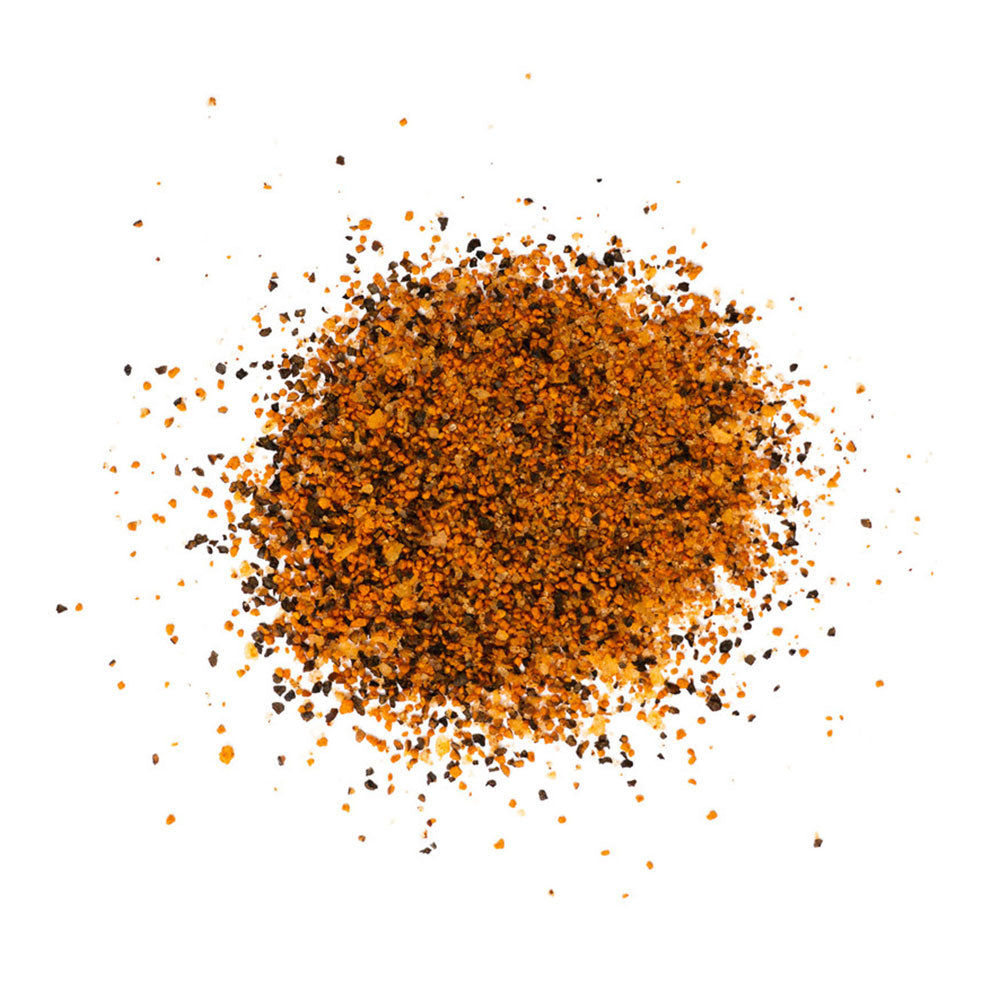 A close-up image of LC BBQ Last Call Dry Rub spices scattered on a white surface. The rub consists of various spices, creating a textured mix of orange and brown granules.