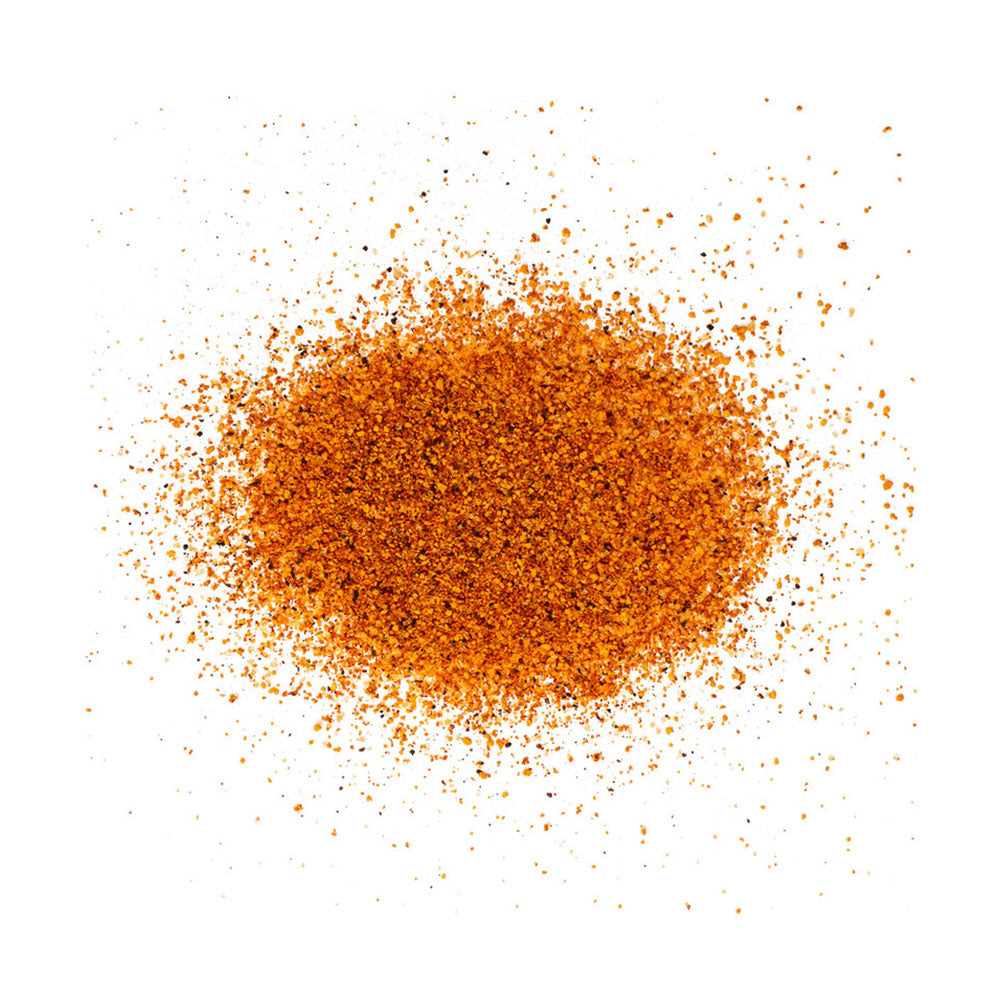 A close-up image of LC BBQ The Honey Hole Competition Rub spices scattered on a white surface. The rub consists of a textured mix of finely ground orange granules.