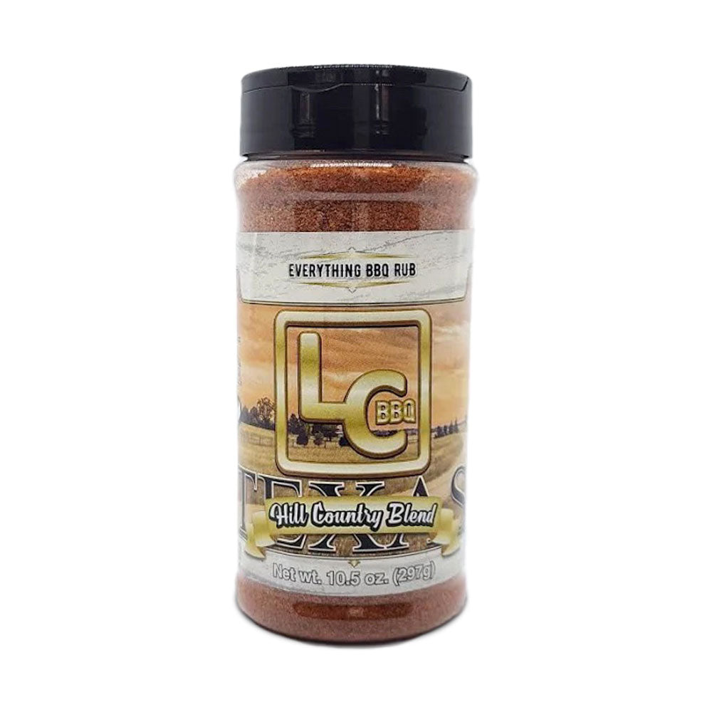 A bottle of LC BBQ Texas Hill Country Blend Everything BBQ Rub viewed from the front. The label features a rural landscape background with the LC BBQ logo and the text "Everything BBQ Rub." The product name "Hill Country Blend" is displayed in a ribbon at the bottom. The label indicates that the bottle contains 10.5 ounces (297 grams) of seasoning.