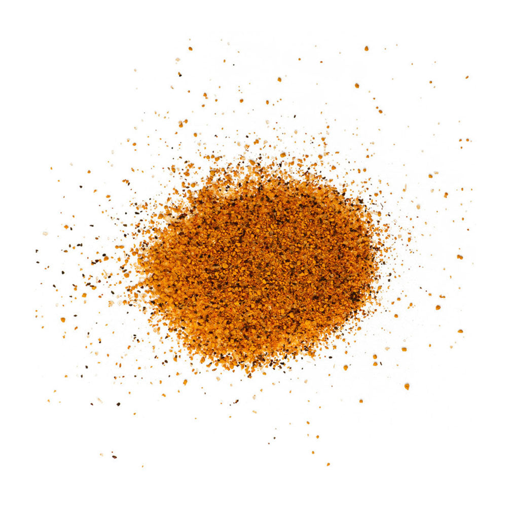 A close-up image of LC BBQ Texas Hill Country Blend Everything BBQ Rub spices scattered on a white surface. The rub consists of a textured mix of orange and brown granules.