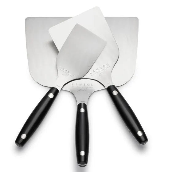 Overlapping trio of stainless steel spatulas with black handles arranged in a fan shape on a white surface.