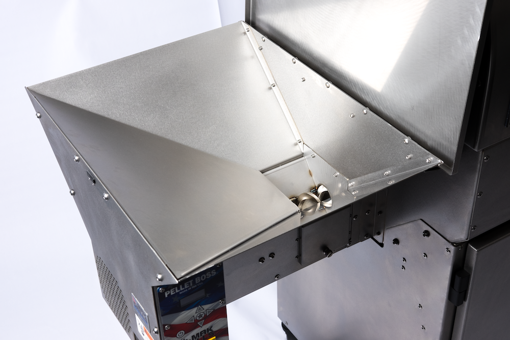 A close-up view of the stainless steel pellet hopper of the grill. The hopper has a sloped design and is attached to the left side of the grill.