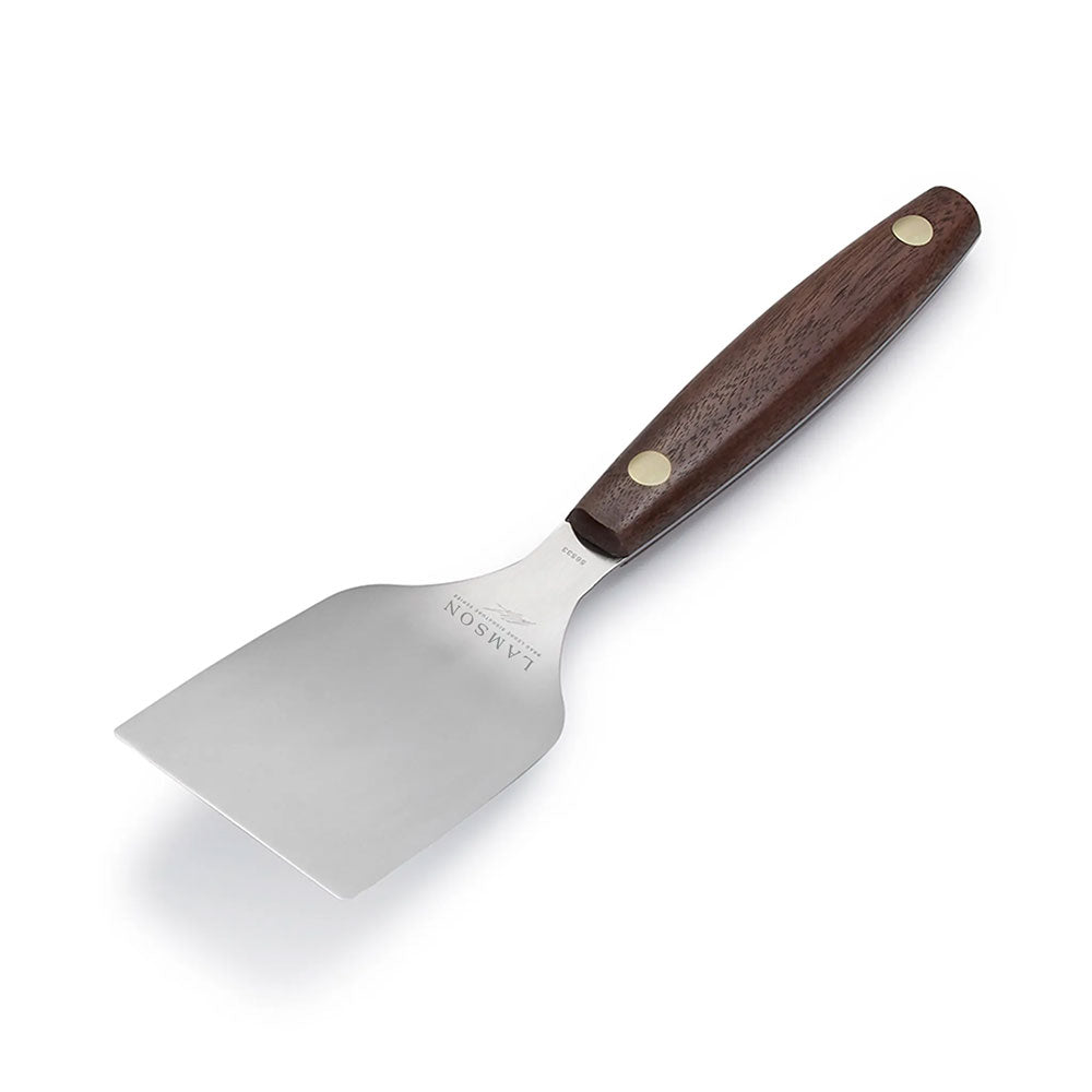 A single Lamson griddle turner with a stainless steel blade and a wooden handle featuring two brass rivets. The turner is shown against a white background, emphasizing its sturdy construction and ergonomic design.