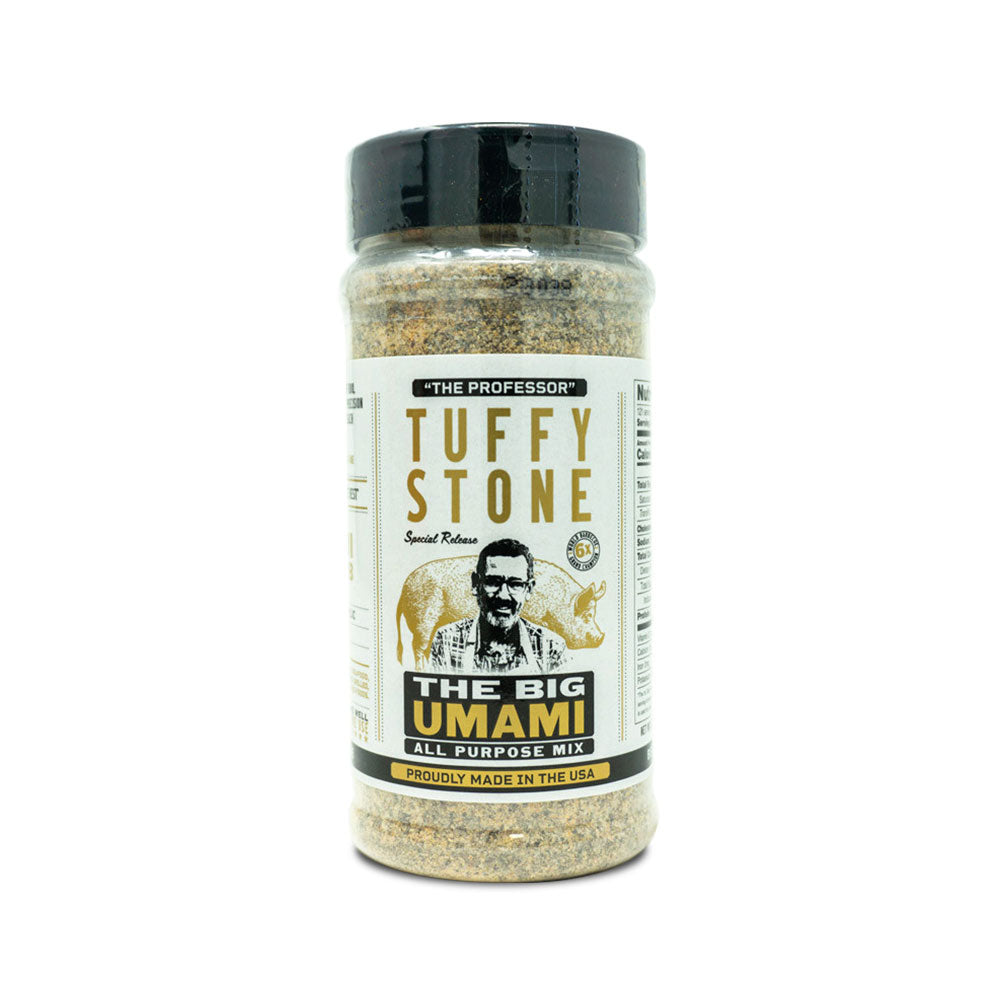 A plastic bottle of Tuffy Stone The Big Umami All Purpose Mix with a black lid. The label features a photo of Tuffy Stone, 'The Professor,' and the product name in gold and black text. The label also mentions that the rub is 'proudly made in the USA.