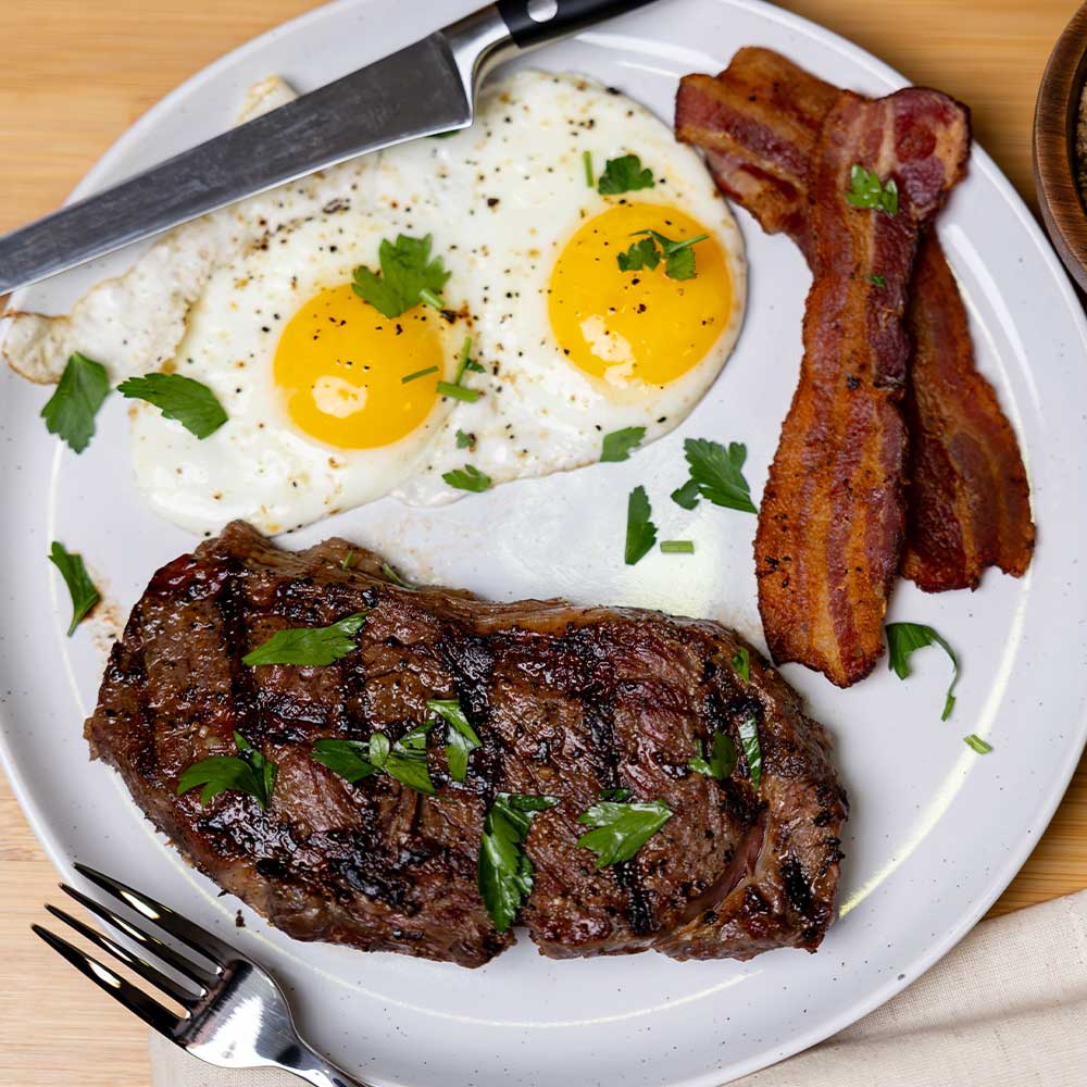 closeup of steak and eggs and bacon with cash cow barbecue seasoning on it