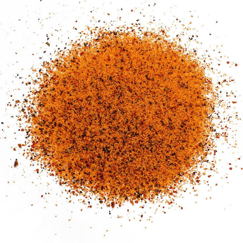A close-up image of EAT Barbecue Sweetness rub granules, showing a mix of orange and black specks of seasoning.