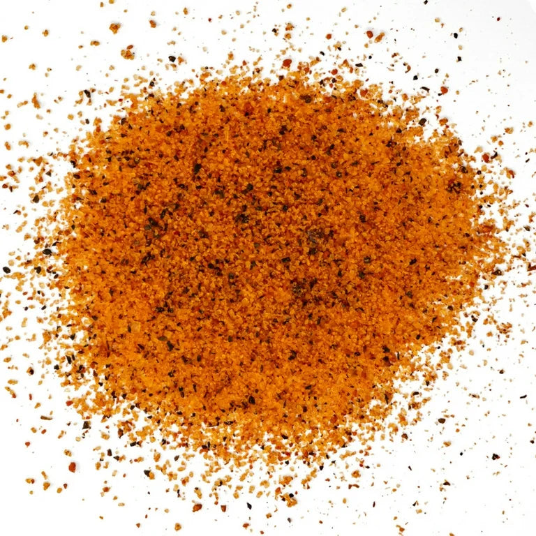 A close-up image of EAT Barbecue Zero to Hero sweet rub granules, showing a mix of orange and black specks of seasoning.