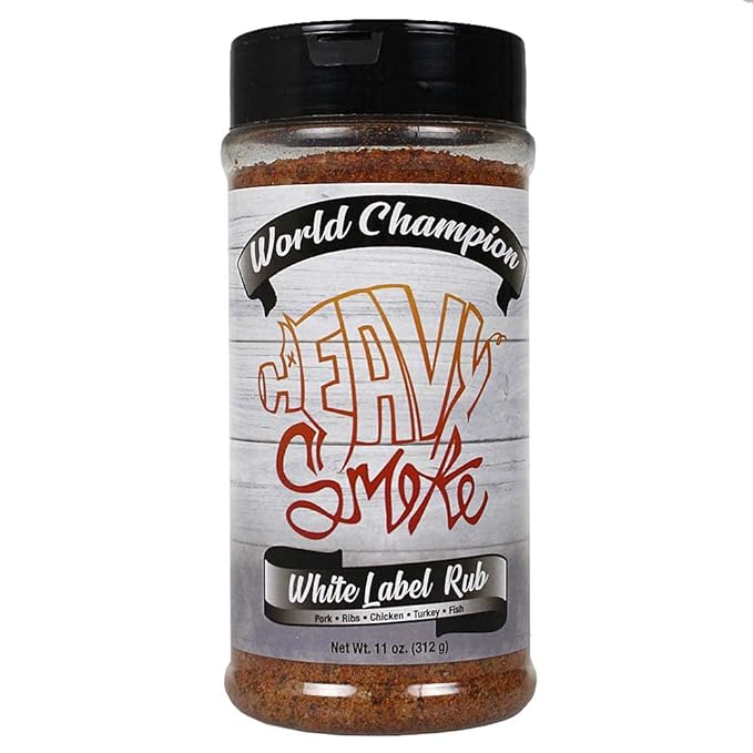 The front of an 11-ounce container of Heavy Smoke White Label Rub. The label features the text "World Champion" at the top, followed by the brand name "Heavy Smoke" in large, stylized letters. Below that, it reads "White Label Rub" with the subtitle "Pork • Ribs • Chicken • Turkey • Fish." The background has a light wood texture.