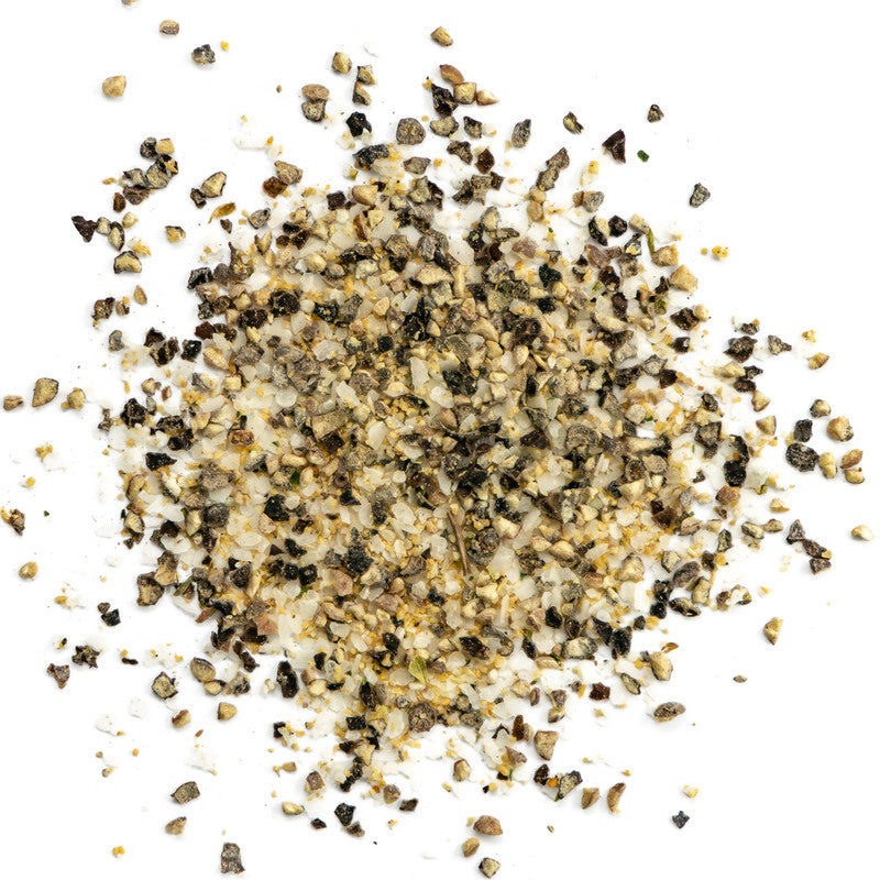 A close-up view of a pile of coarsely ground, mixed seasoning, primarily consisting of black pepper, salt, and other spices. The texture is rough, with various shades of black, white, and light brown grains.