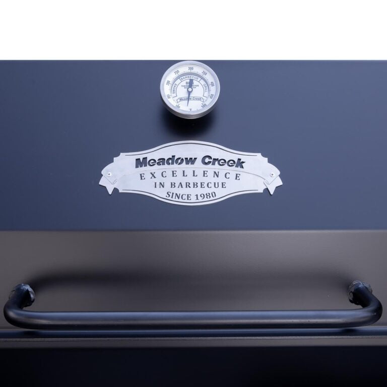 A close-up of the thermometer and handle on the Meadow Creek pig roaster, highlighting the temperature gauge and metal handle for easy operation.