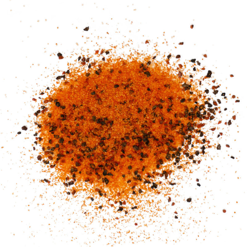 A close-up view of a pile of Meat Church Dia de la Fajita Seasoning. The spice mix is a coarse, reddish-orange powder with visible black pepper flakes.