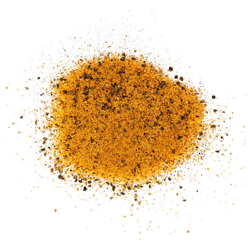 A close-up view of a pile of Meat Church Texas Sugar BBQ Rub. The spice mix is a coarse, orange powder with visible black pepper flakes.