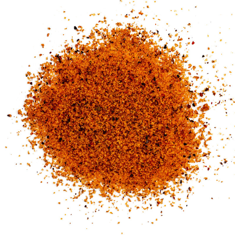 A pile of The Gospel All Purpose Rub seasoning, consisting of finely ground orange and black spices.