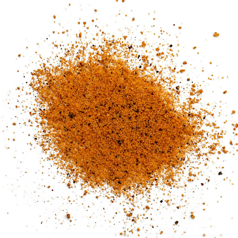 A close-up view of a pile of Meat Church Honey Bacon BBQ Rub. The spice mix is a coarse, reddish-brown powder with visible black pepper flakes.