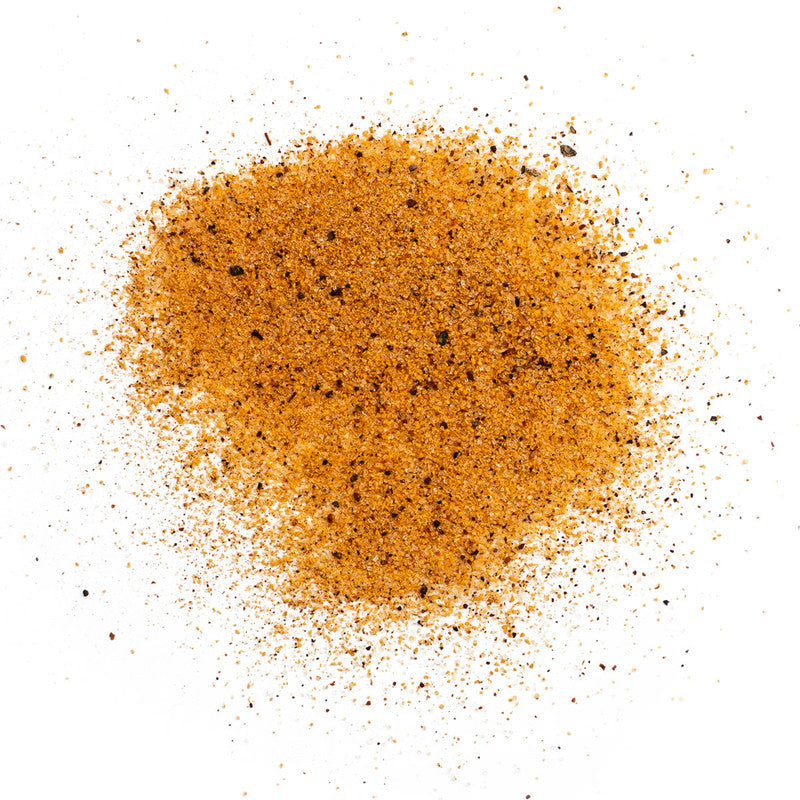 A close-up view of a pile of Meat Church Honey Hog BBQ Rub. The spice mix is a coarse, reddish-brown powder with visible black pepper flakes.