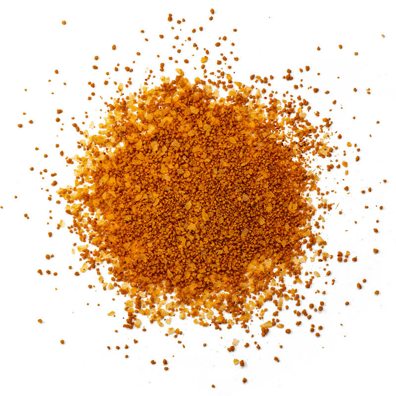 A close-up view of Simply Marvelous The Genie's Hooch Rub, showing a mixture of finely ground orange and brown granules with various spices and seasonings.