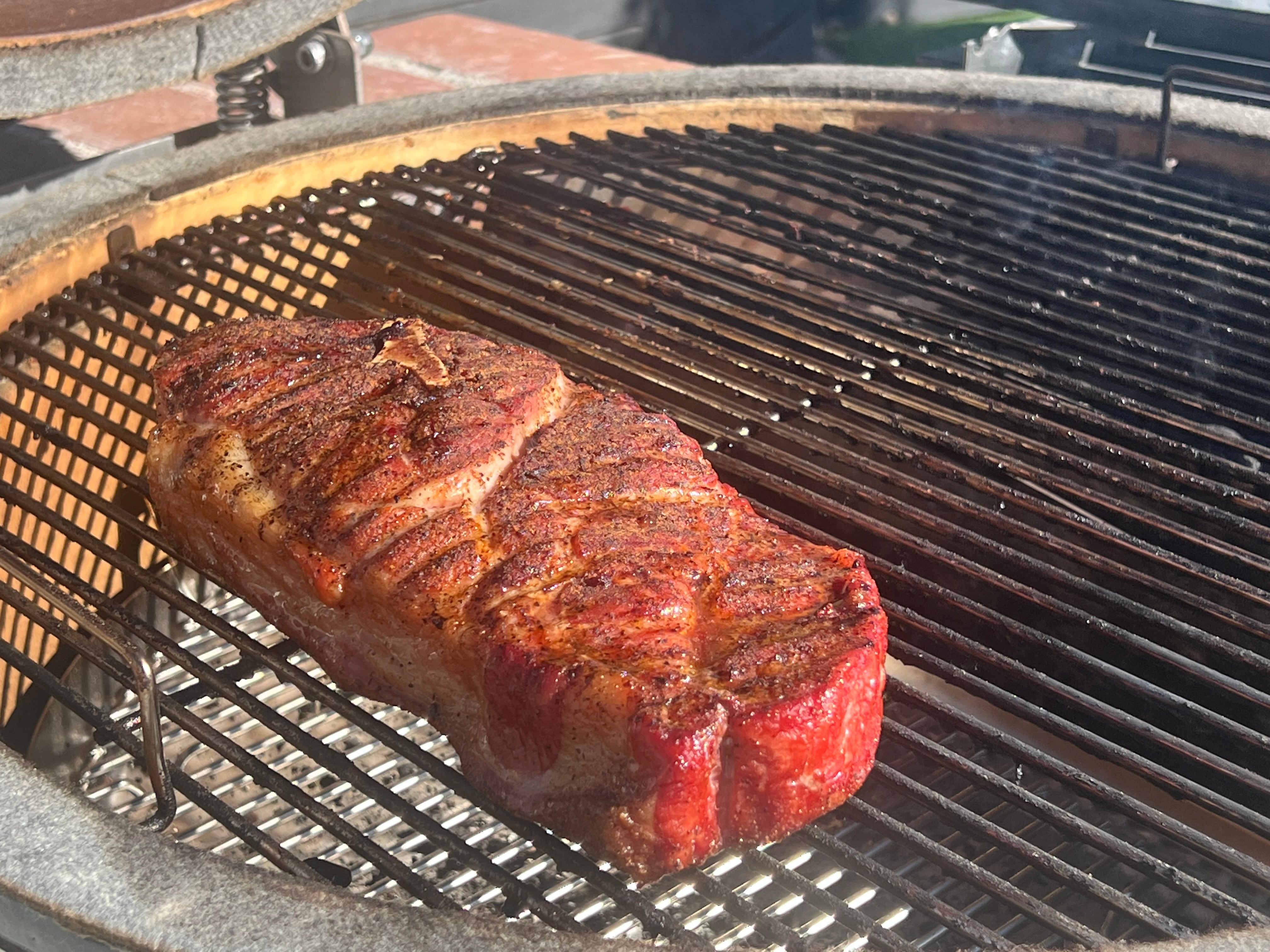 Pork steak on a grill with a nice brown bark seasoned with Big Poppa's Sweet Money Hot Seasoning 