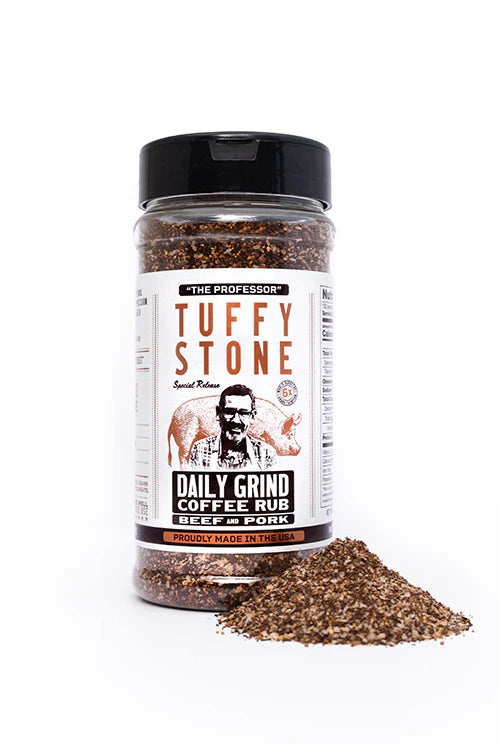 A close-up view of Tuffy Stone Daily Grind Coffee Rub for beef and pork with the label visible, showing the brand name, a picture of Tuffy Stone, and the product description. A small pile of the seasoning is placed in front of the bottle.