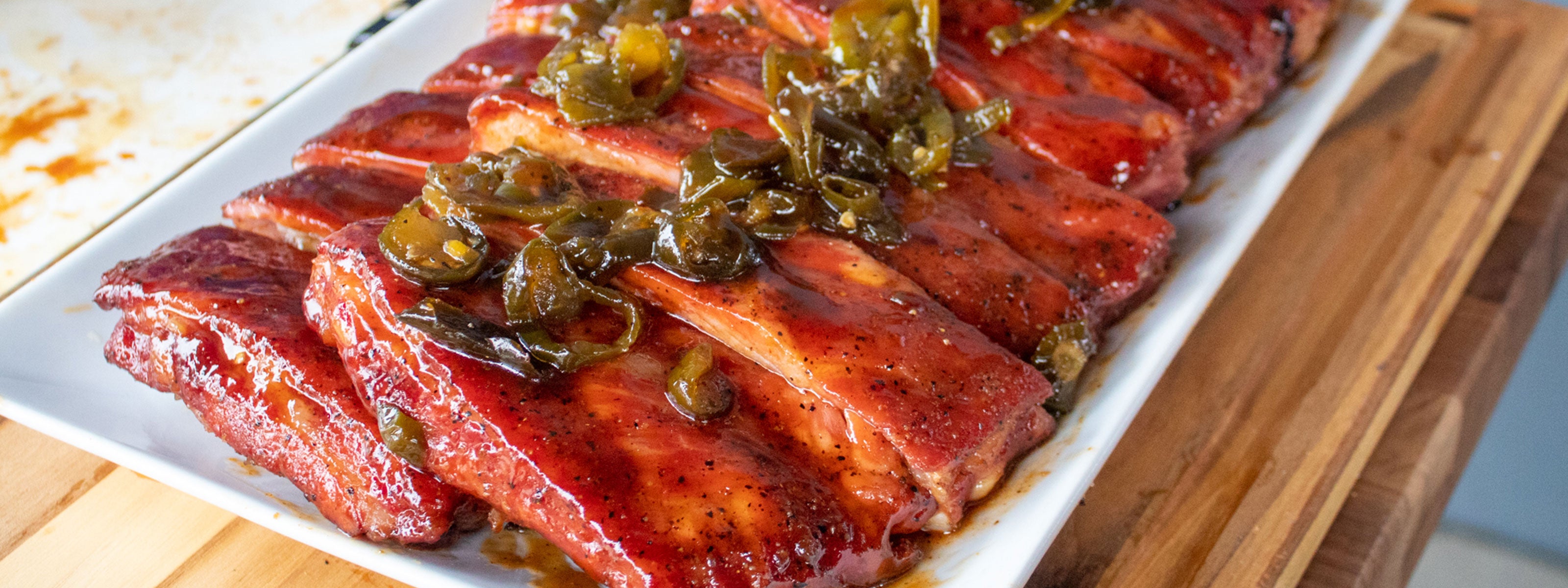 Plate of mouthwatering ribs seasoned with Big Poppa's Sweet Money, topped with Granny's Sauce and slices of jalapeno.