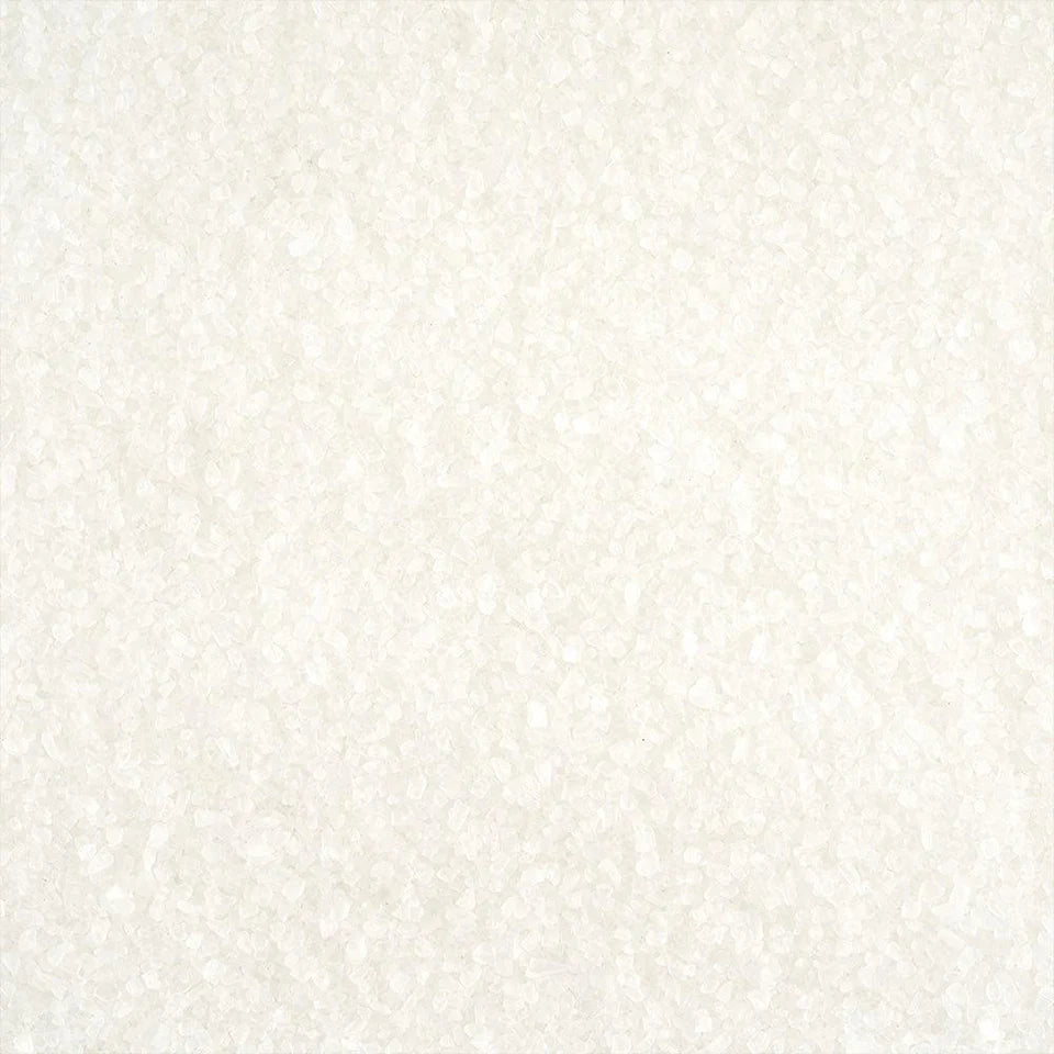 A close-up view of coarse white salt grains spread evenly on a flat surface.