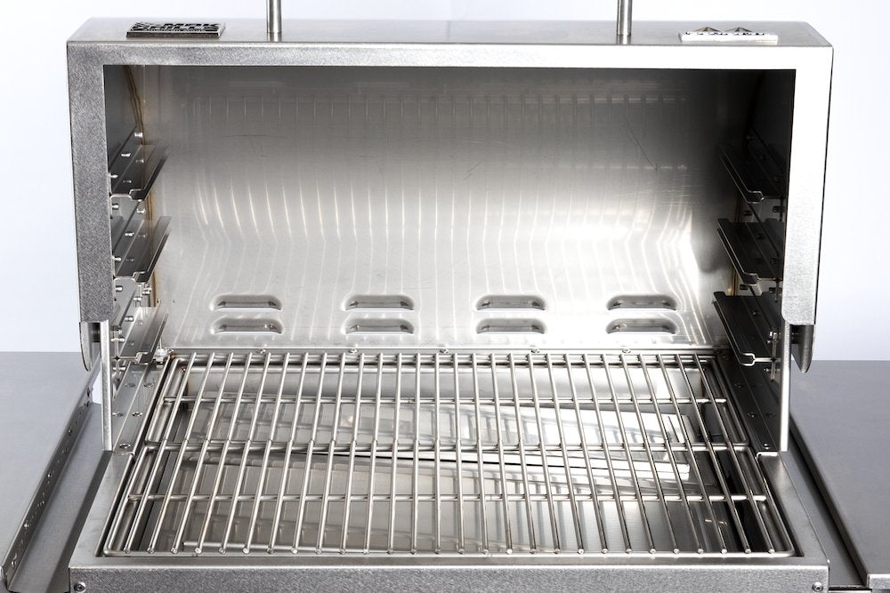 The inside view of the grill's main cooking area, showing the stainless steel cooking grates and the interior walls. The back wall has multiple ventilation slots.