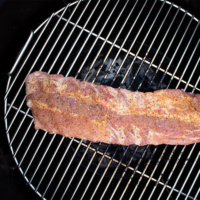 A slab of meat seasoned with Big Poppa's Sweet Money Seasoning on a grill grate, showing the seasoning's rich color and texture on the surface of the meat.