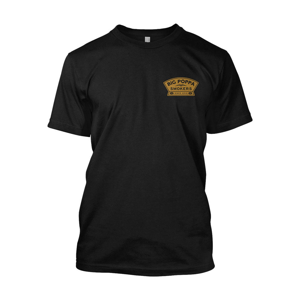 Front view of a black T-shirt with a small logo on the left chest that reads 'Big Poppa Smokers' in gold and white text, featuring an illustration of a cow.