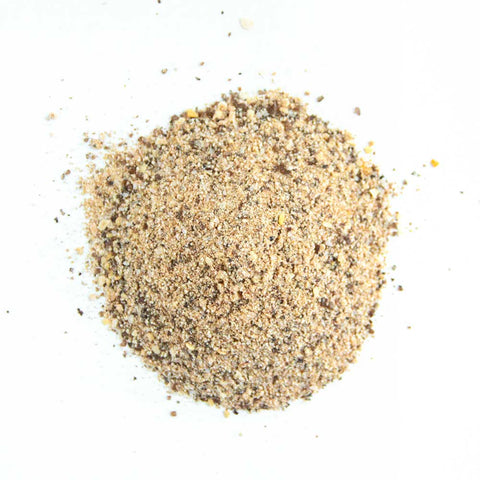 Close-up view of a beige and brown mixed seasoning pile, consisting of coarse salt, herbs, and spices, displayed on a white background.
